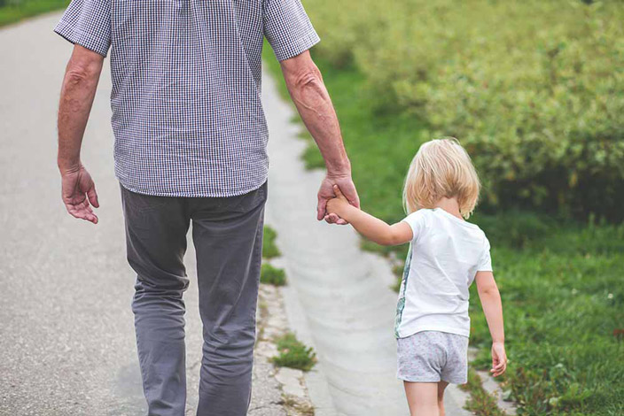 old man holding hands  with grandchild walking